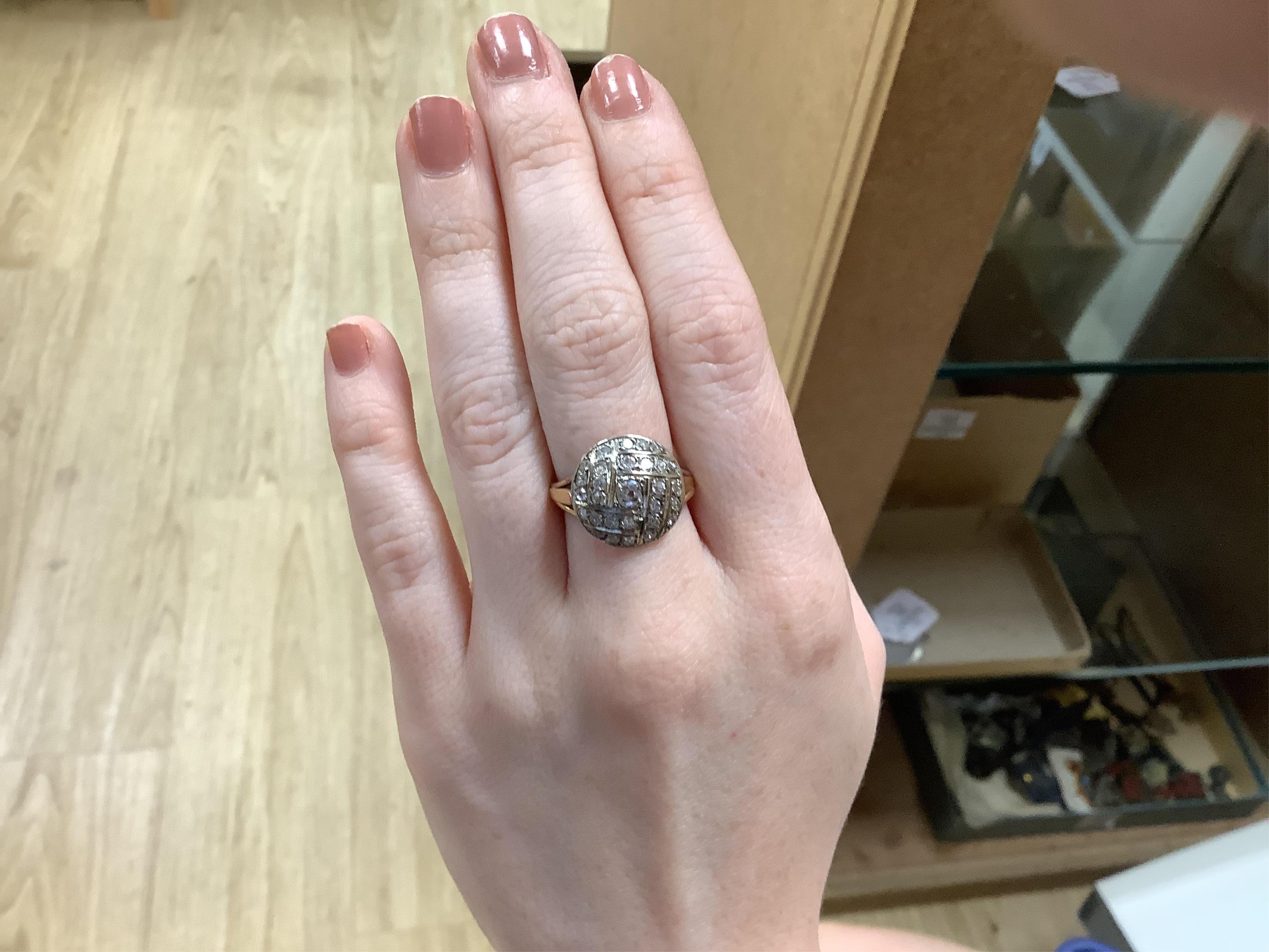 A diamond ring, centring on a circular motif of bombé design, set with geometric arrangements of cushion-shaped, single- and circular-cut diamonds totalling approximately 0.90 carats, to a gold band, size M1/2, indistinc